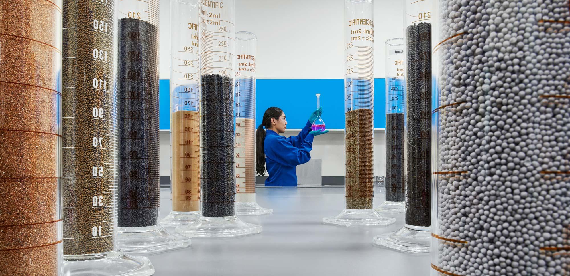 Female engineering looking at beakers with solid samples in a Learning Center, Abu Dhabi